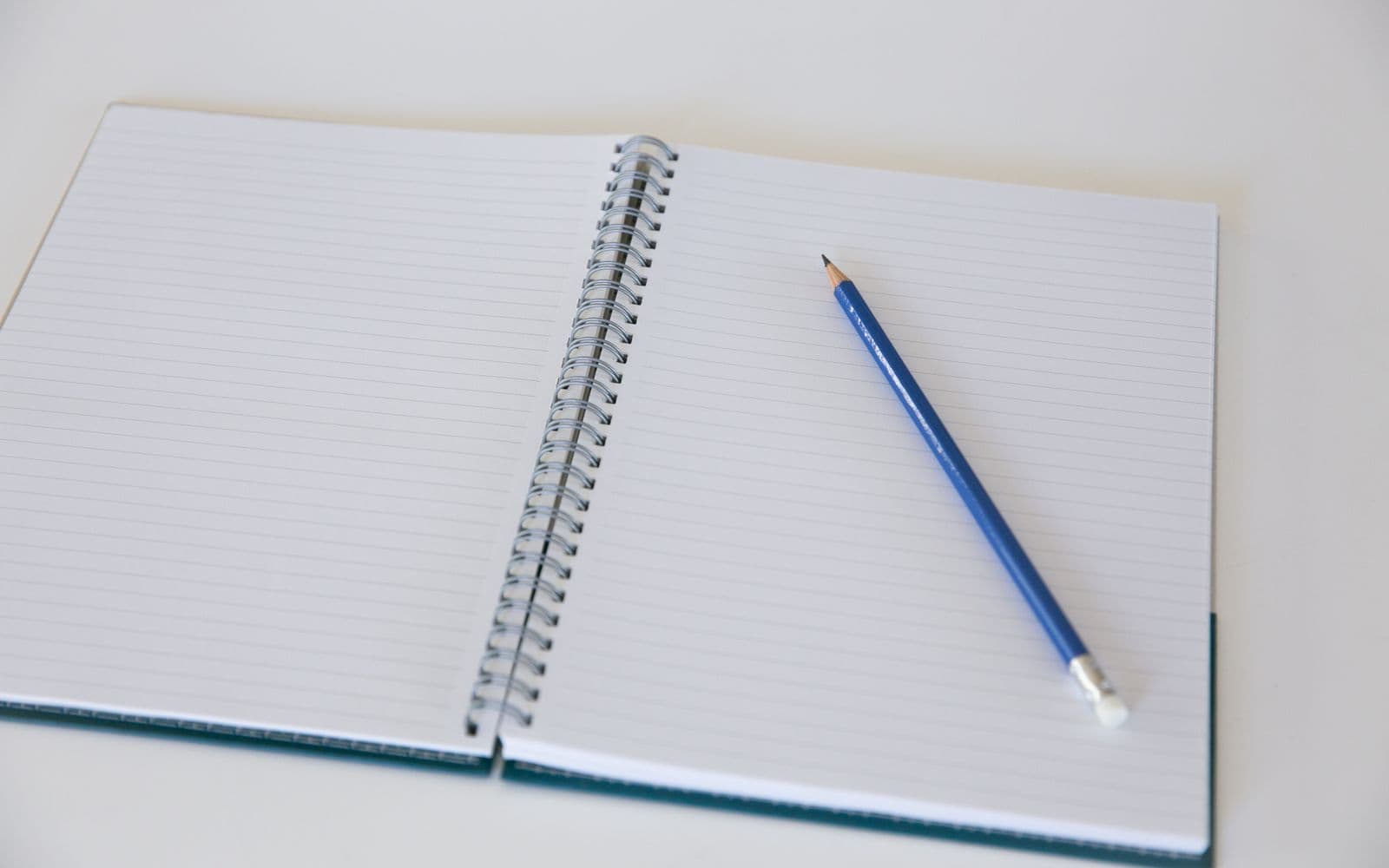 An open coil-bound notebook with lined pages and a pencil